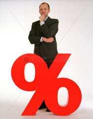 Ein Mann mit Anzug steht hinter einem Prozentzeichen