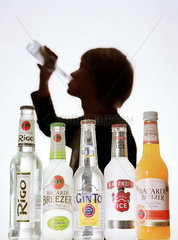 Umriss eines trinkenden jungen Mannes mit Alcopopflaschen