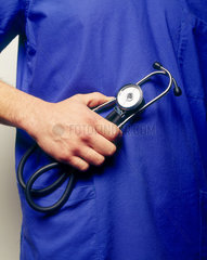 Mediziner haelt ein Stethoskop in der Hand vor seinem Kittel
