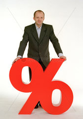 Ein Mann mit Anzug steht hinter einem Prozentzeichen