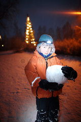 Belloe  Schweden  Nachtaufnahme  Junge mit Stirnlampe haelt eine Schneekugel fest