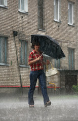 Scucyn  Weissrussland  eine Frau mit Regenschirm bei sehr starkem Regen