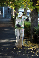 Tokio  Japan  Mann fegt Ginkgoblaetter von der Strasse