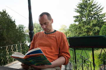 Gallin-Kuppentin  Deutschland  ein Mann sitzt auf einer Terrasse und liest ein Buch