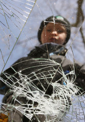 Symbolfoto schwere Kindheit  Junge schaut in einen zerbrochenen Spiegel