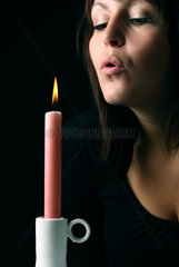 Berlin  Deutschland  junge Frau pustet eine Kerze aus