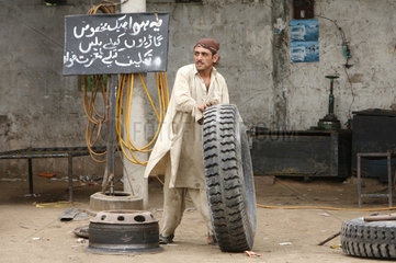 Karatschi  Pakistan  Mann rollt einen LKW-Reifen