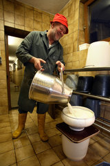 Tirol  ein Bauer giesst frisch gemolkene Milch durch ein Sieb in einen Eimer