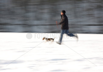 Berlin  Deutschland  ein Mann mit Hund rennt auf dem zugefrorenen Schlachtensee