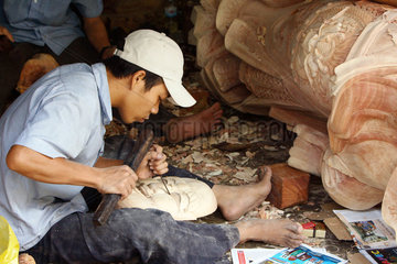 Vietnam  Handwerker schnitzt konzentriert eine traditionelle Holzmaske