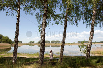 Linum  Deutschland  Frau sitzt an einem Fischteich in Linum