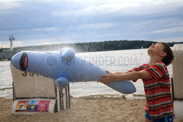 Berlin  Deutschland  ein Junge steht mit seinem Gummitier unter der Stranddusche