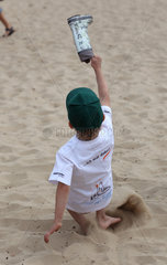 Berlin  Deutschland  Junge am Strand wirft seinen Gummistiefel in die Luft