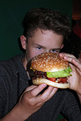 Berlin  Deutschland  Junge isst einen Burger