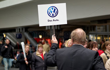 Berlin  Deutschland  Mann haelt ein Schild mit VW-Logo hoch