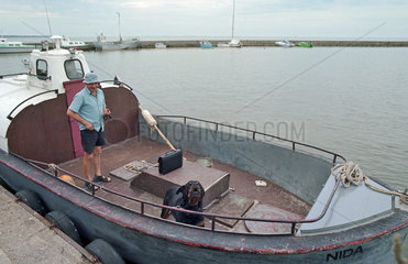 Fischer auf seinem Boot im Hafen von Nidden  Litauen