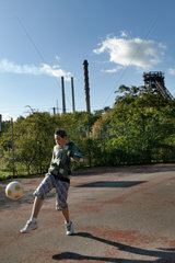 Duisburg  Deutschland  Junge spielt auf einem Sportplatz Fussball