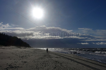Kolberg  Polen  Frau laeuft bei Sonnenschein allein am Strand entlang