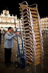 Salamanca  Spanien  Angestellter transportiert gestapelte Stuehle