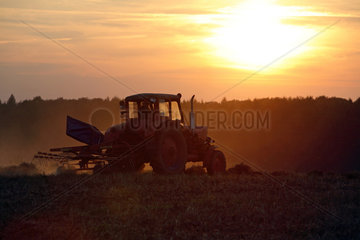 Prangendorf  Deutschland  Symbol Hitze  Traktor bei Sonnenuntergang auf dem Feld
