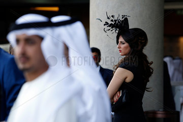 Dubai  Vereinigte Arabische Emirate  elegant gekleidete Frau mit Hut und Maenner in Landestracht beim Pferderennen