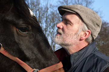 Neu Kaetwin  Deutschland  Mann schaut sein Pferd an