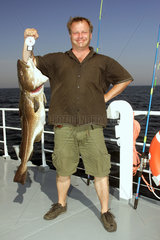 Wismar  Angler zeigt stolz seinen frisch gefangenen Dorsch