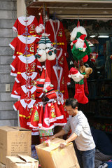 Ein Verkaefer packt aus Pappkartons Weihnachtsbekleidung fuer Kinder aus