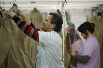 Istanbul  Tuerkei  Mitarbeiter haengen fertig gebuegelte Maentel in einer Textilfabrik auf