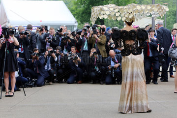Ascot  Grossbritannien  elegant gekleidete Frau mit Hut posiert vor einer Reihe Fotografen