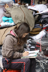 Verkaeferin am Cho Dong Xuan Markt fuehrt Buch ueber ihre Verkaeufe