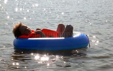 Neukloster  Deutschland  Kind mit Schwimmweste schlaeft in einem Schlauchboot