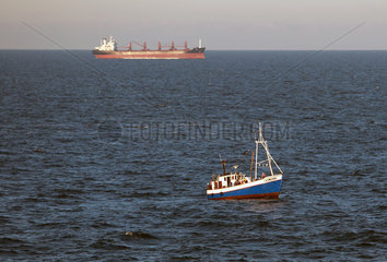 Warnemuende  Deutschland  Fischkutter und leeres Containerschiff auf der Ostsee