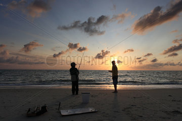 Hvide Sande  Daenemark  zwei Jungen angeln bei Sonnenuntergang