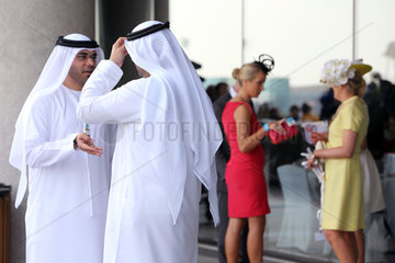 Dubai  Vereinigte Arabische Emirate  Maenner in Landestracht und elegant gekleidete Frauen