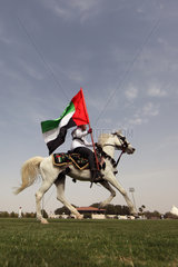 Dubai  Reiter mit Nationalflagge auf einem Arabischen Vollblutpferd