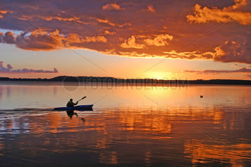 Ploen  Deutschland  ein Kanufahrer paddelt bei Sonnenuntergang auf dem grossen Ploener See