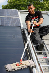 Berlin  Deutschland  Auszubildende putzt einen Solarkollektor