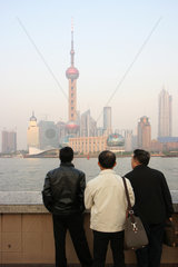 Shanghai  drei Maenner am Bund schauen auf Pudong