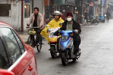 Shanghai  Motorradfahrer mit Mundschutz auf der Strasse