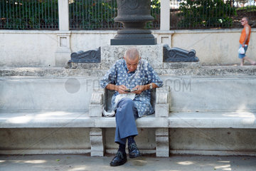 Havanna  Kuba  ein Mann sitzt am Prado und liest