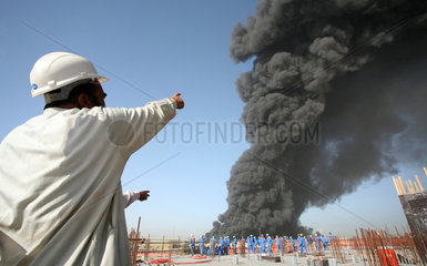 Dubai  Vereinigte Arabische Emirate  Bauarbeiter zeigt auf eine schwarze Rauchwolke