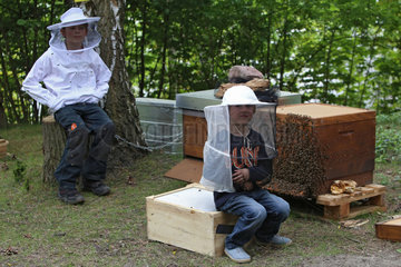 Berlin  Deutschland  Kinder mit Imkerhut sitzen stolz vor Bienenbeuten