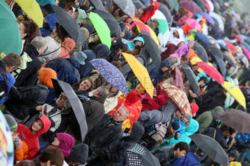 Hoppegarten  Deutschland  Menschen stehen bei Schlechtwetter unter ihren Regenschirmen