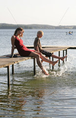 Ploen  Deutschland  eine junge Frau entspannt mit ihrem Sohn auf einem Bootssteg