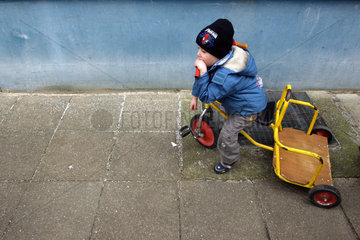 Berlin  Junge sitzt in gedankenverloren auf einem Kinderroller