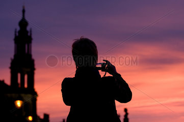 Dresden  Deutschland  Frau fotografiert den Sonnenuntergang  im Hintergrund die Hofkirche