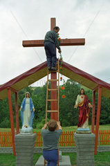 Maenner beim Schmuecken eines Kreuzes  Polen