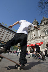 Peking  Jugendliche fahren vor einer Kirche Skateboard
