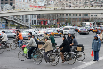 Peking  Fahrradfahrer ueberqueren die Strasse